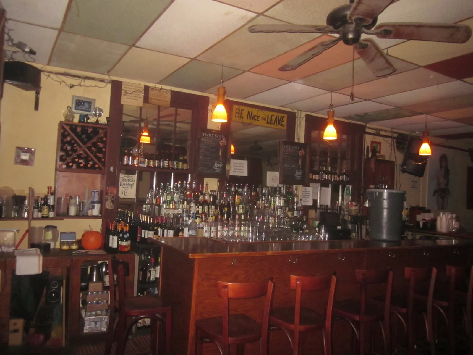 Balcão de bar de madeira com garrafas e banquetas