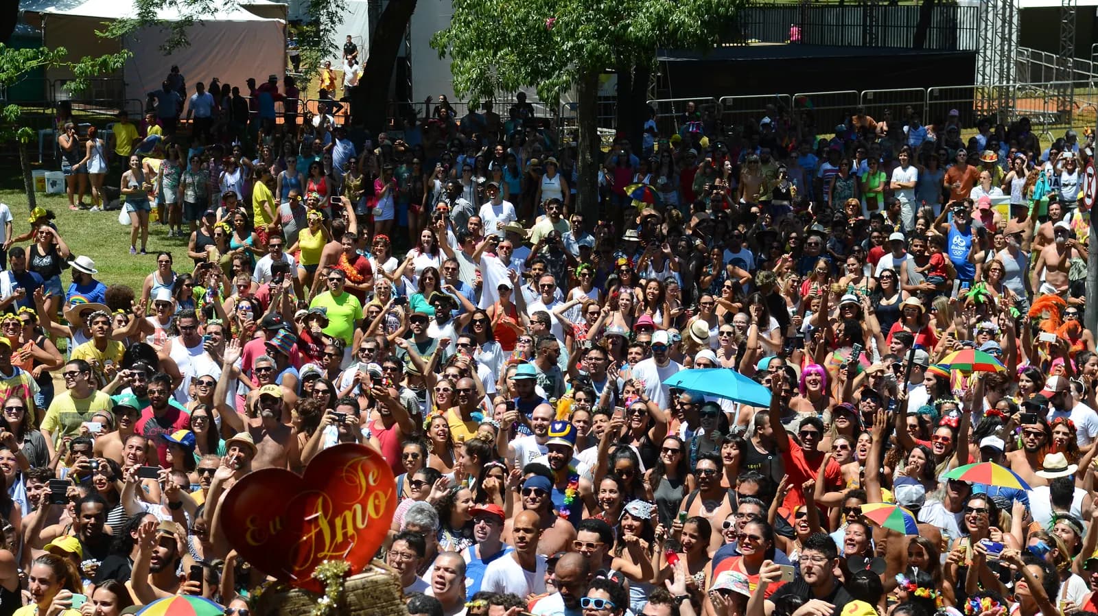 Multidão de foliões com guarda-chuvas coloridos acompanhando um bloco de rua em São Paulo